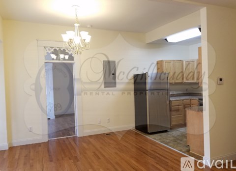 A room with a chandelier and a fridge in it.