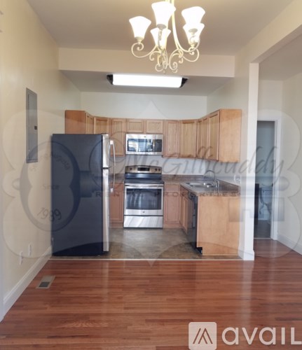 A kitchen with wooden cabinets and a black fridge.