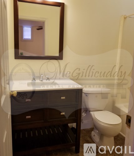 A bathroom with a toilet, sink, and mirror.