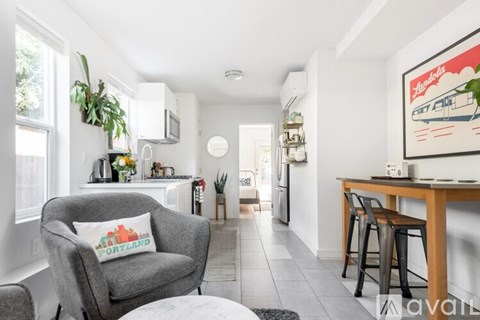 A living room with a grey armchair and a painting on the wall.