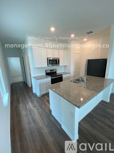A kitchen with a granite countertop and a TV on the wall.