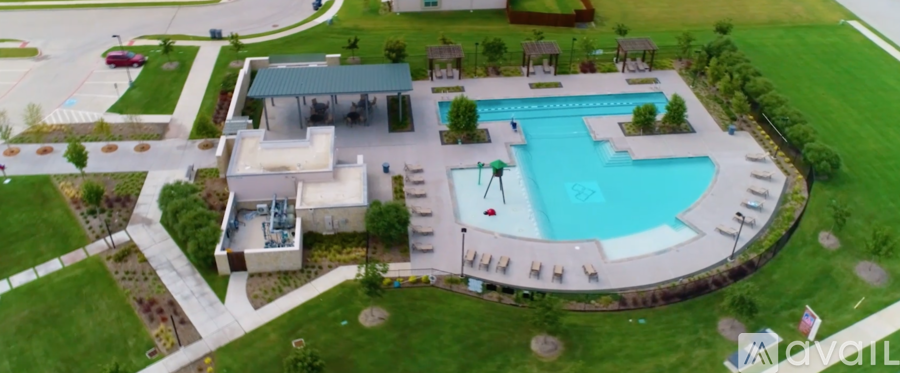 A large swimming pool surrounded by a concrete border and a small building with a green roof.