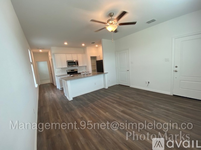 A well-lit, spacious room with a ceiling fan and hardwood flooring.