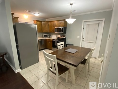 A kitchen with a table and chairs in the foreground and a refrigerator in the background.