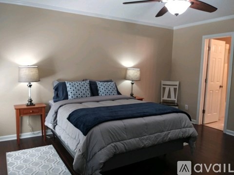 A bedroom with a bed, two lamps, and a ceiling fan.