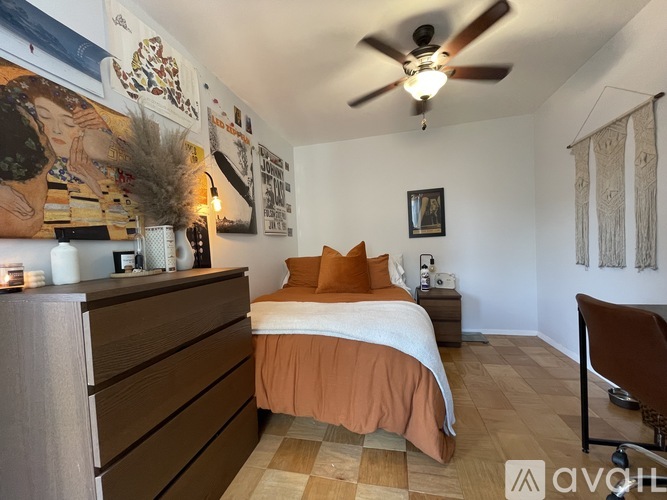 A bedroom with a bed, dresser, and ceiling fan.