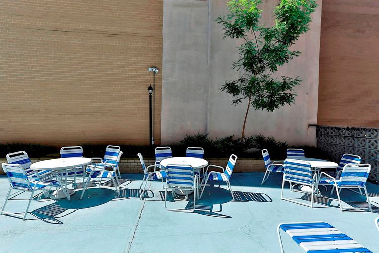 A poolside area with blue and white striped chairs and tables.