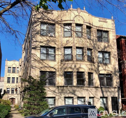 A beige building with a tree in front of it.