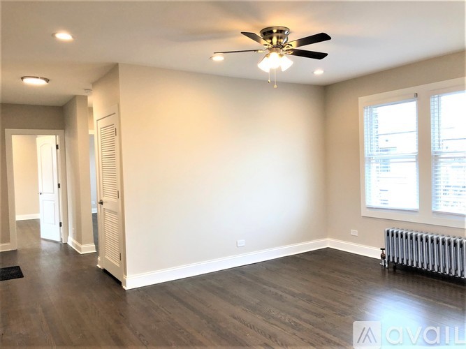 A spacious room with a ceiling fan and a radiator on the wall.