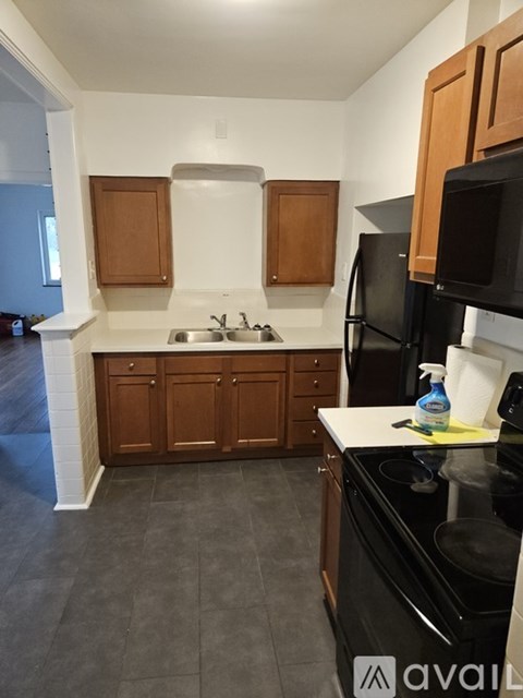 A kitchen with black appliances and wooden cabinets.
