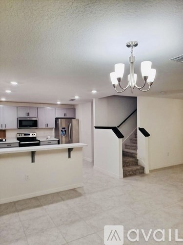 A chandelier hangs over a kitchen island with a sink and a microwave.
