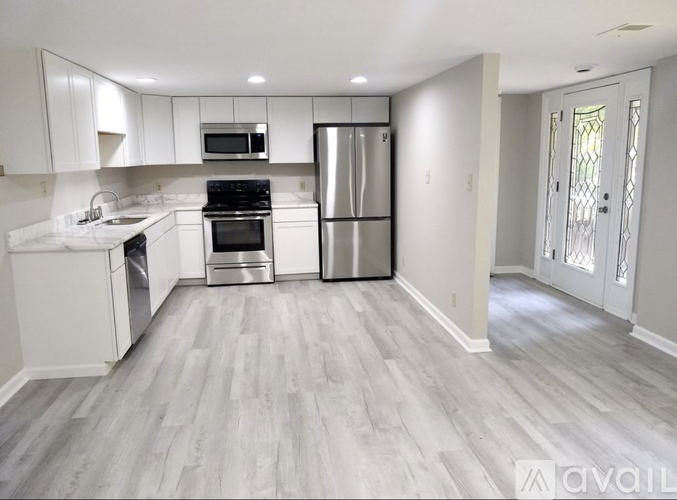 A kitchen with white cabinets and a grey floor.