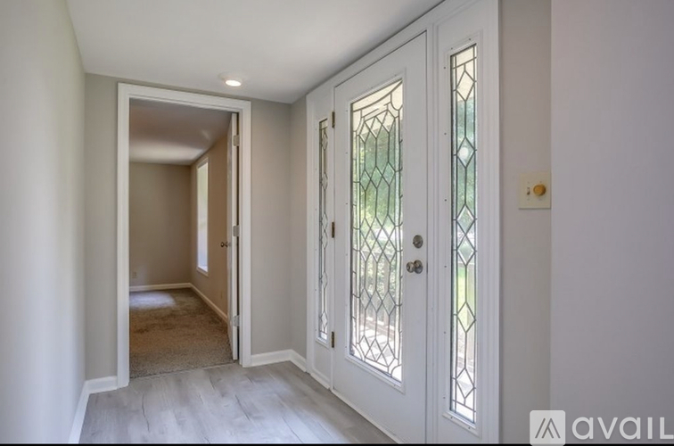 A hallway with a white door and a glass door.