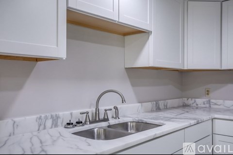 A kitchen with a marble countertop and white cabinets.