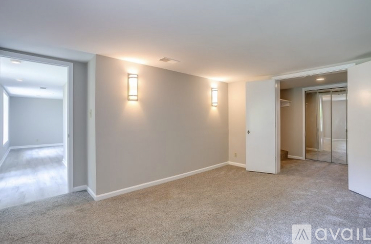 A spacious room with carpeted floor and two wall-mounted lights.