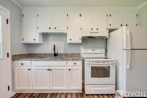 A kitchen with white cabinets and a granite countertop.