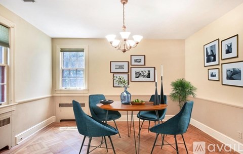A dining room with a table set for four and a chandelier hanging from the ceiling.