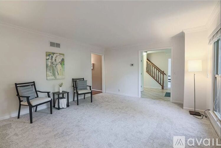 A living room with two chairs and a table with a vase of flowers on it.