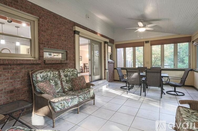 A sunny day in a living room with a sofa, chairs, and a fan.