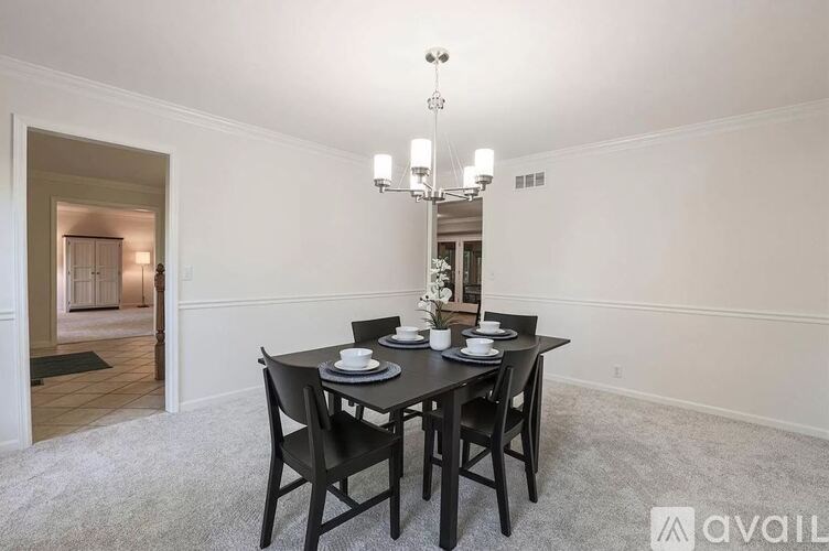 A dining room with a table set for two and a chandelier.