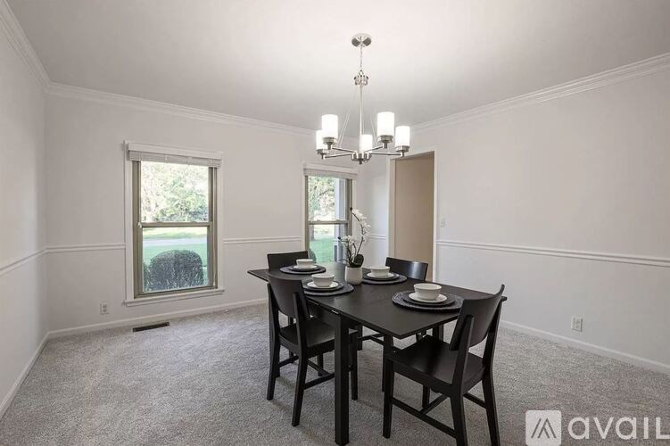 A dining room with a table set for two and a chandelier.