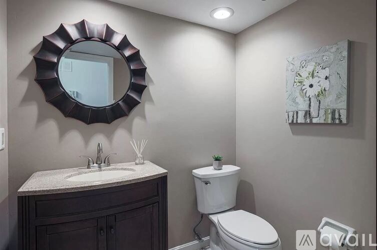 A bathroom with a toilet, sink, and mirror.