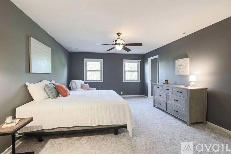 A bedroom with a bed, dresser, and ceiling fan.
