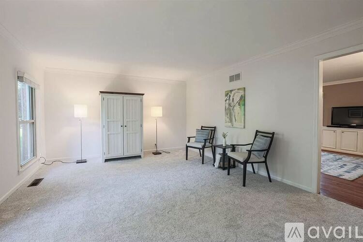 A room with a white carpet and a painting on the wall.