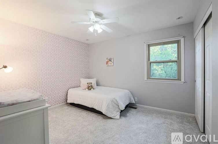 A bedroom with a bed, dresser, and window.