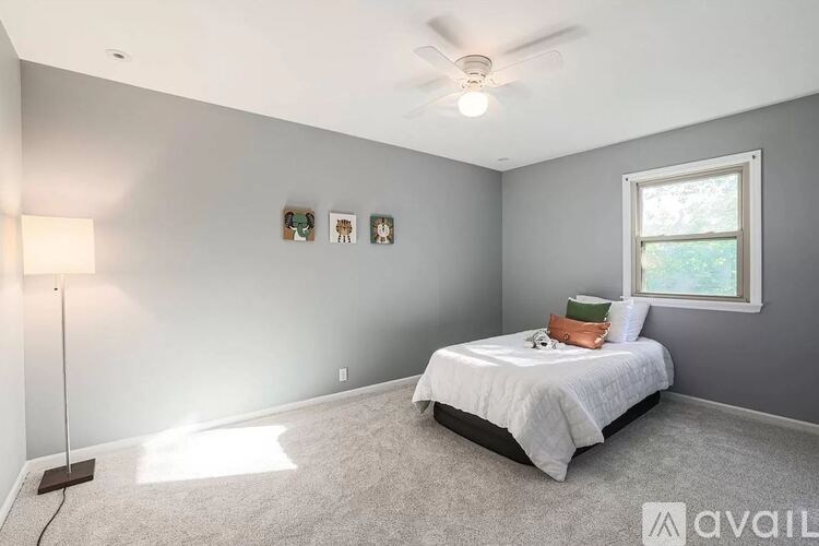 A bedroom with a bed, a ceiling fan, and a window.