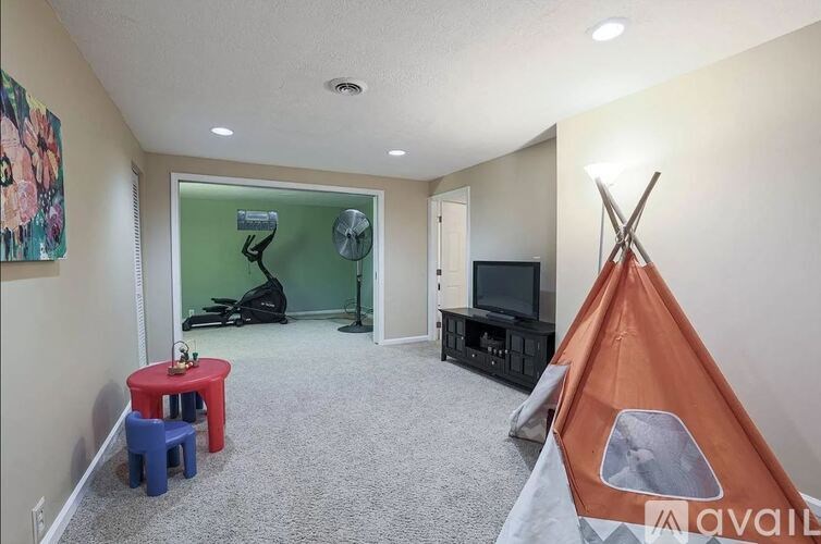 A room with a teepee, a red table, and a TV.