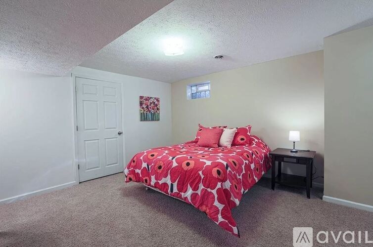 A bedroom with a bed covered in a red and white patterned bedspread.