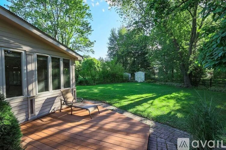 A wooden deck with a chair is in front of a house.
