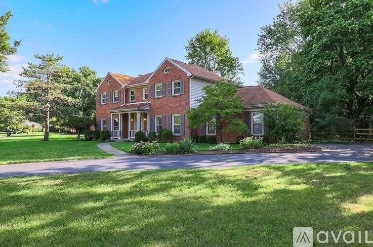 A large red brick house with a driveway in front.