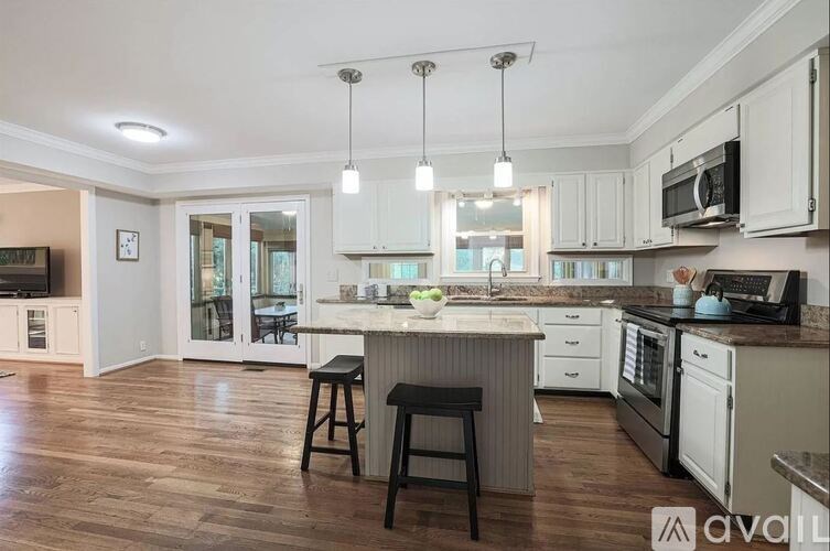 A kitchen with white cabinets and a wooden floor.