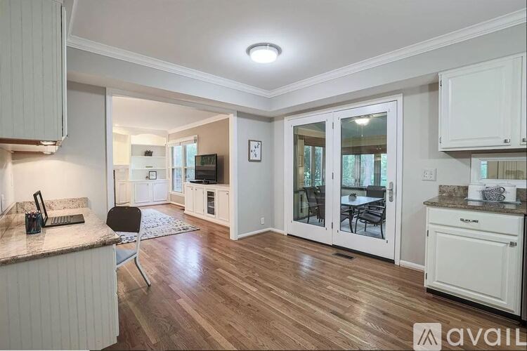 A kitchen with white cabinets and a wooden floor.