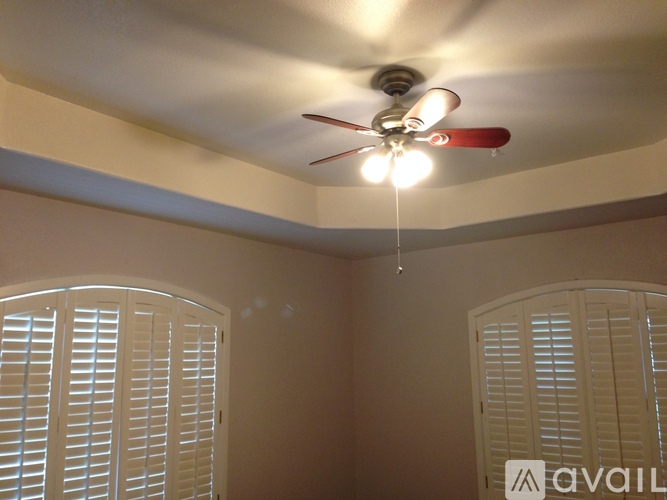 A room with a ceiling fan and closed white shutters.