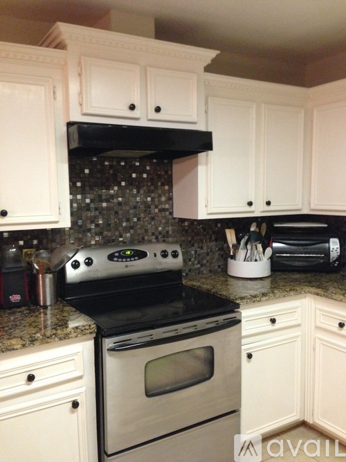 A kitchen with white cabinets and a black stove top oven.