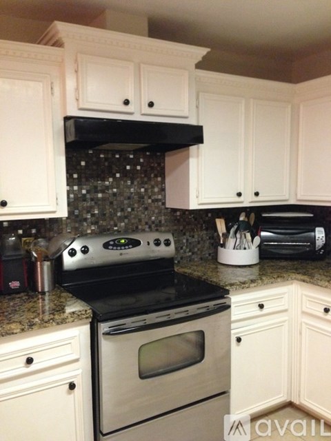 A kitchen with white cabinets and a black stove top oven.