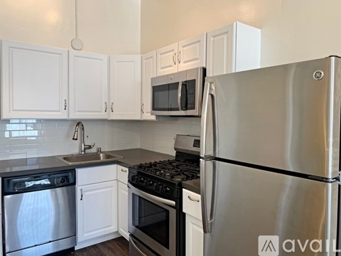 A kitchen with white cabinets and a stainless steel refrigerator.