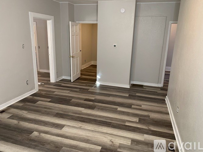 A hallway with wood flooring and white walls.