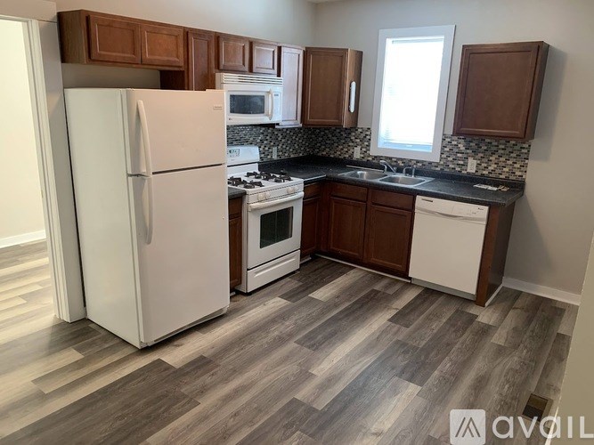 A kitchen with a white refrigerator, wooden cabinets, and a tiled backsplash.