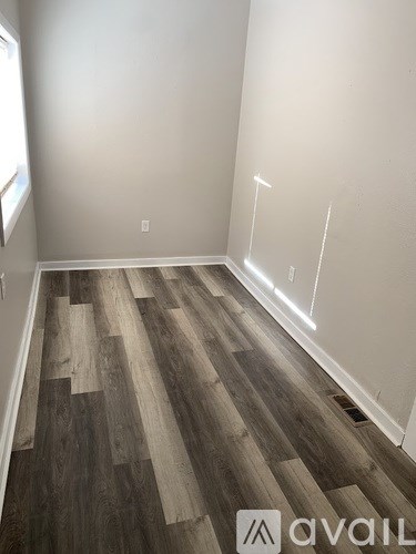 A room with wooden flooring and white walls.