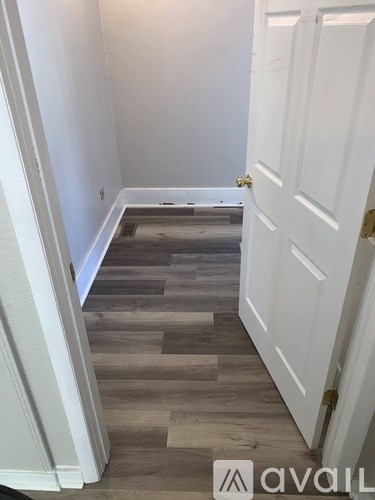 A hallway with a white door and wooden flooring.