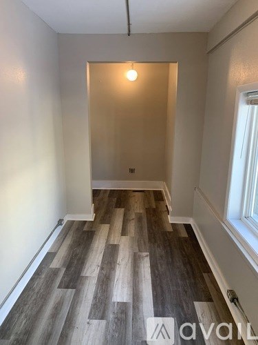 A room with wooden flooring and a window on the right side.