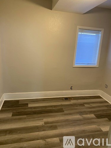 A room with wooden flooring and a window with blinds.