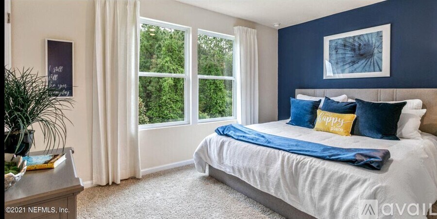 A bedroom with a large bed and a window overlooking greenery.