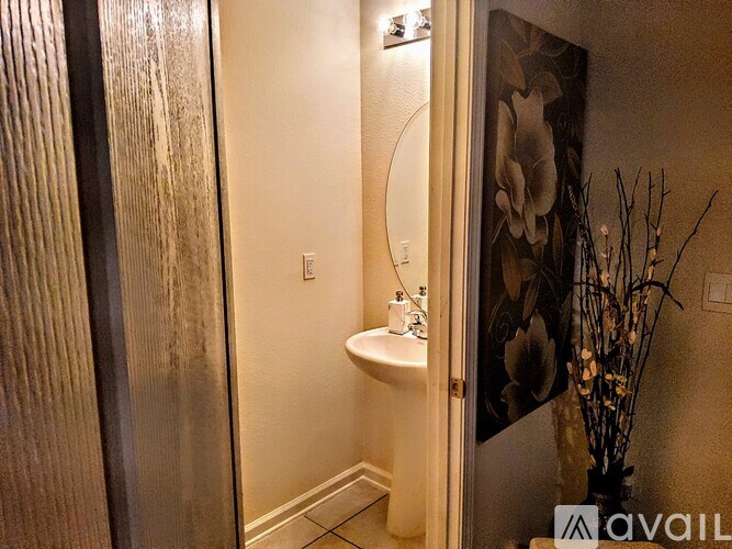A bathroom with a toilet, sink, and a vase of dried flowers.