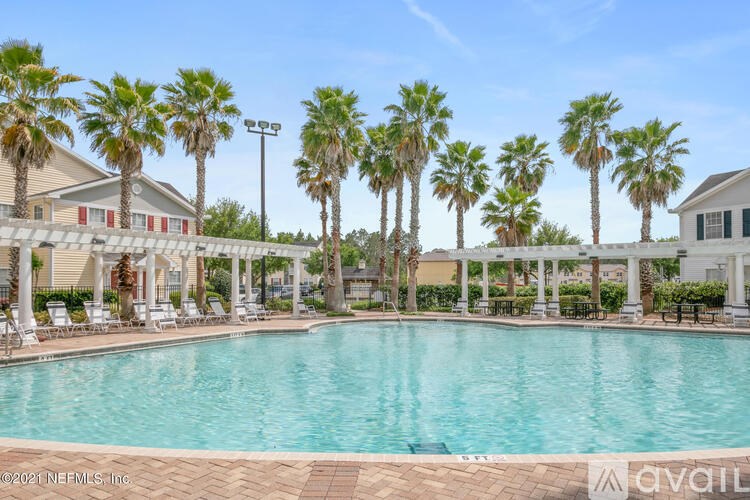 A pool surrounded by palm trees and lounge chairs.