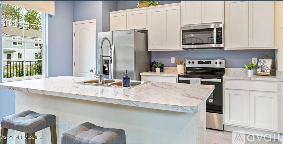 A kitchen with a marble countertop and stainless steel appliances.
